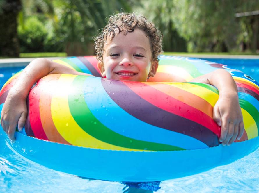 Niño bañándose en la piscina con flotador